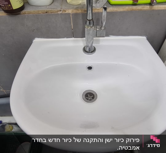 כיור לבן עם ברז מתכת, צינור אפור מתחת